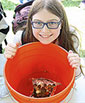 smiling girl with orange 5-gal bucket with floating pennies