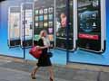 Woman walking past phone ads