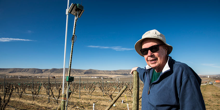 Jim Holmes stands next to a sensor that monitors the vineyard’s soil moisture year-round.