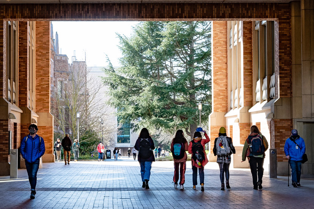 Students walking through arch passing by Allen Library