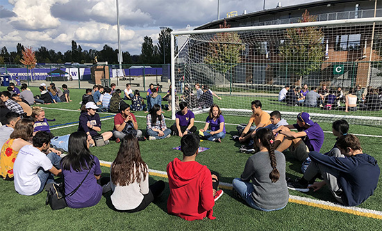 students sitting in circles on a soccer field