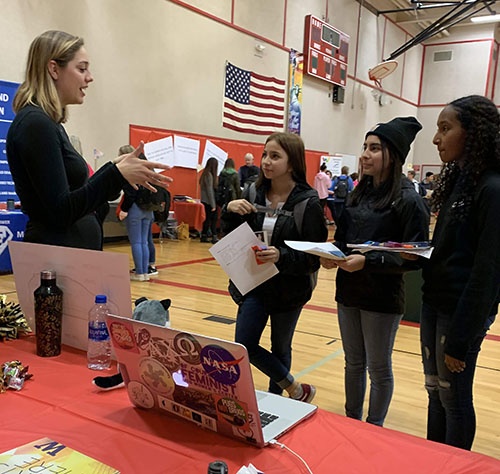 Student speaking to three girls in a gymnasium