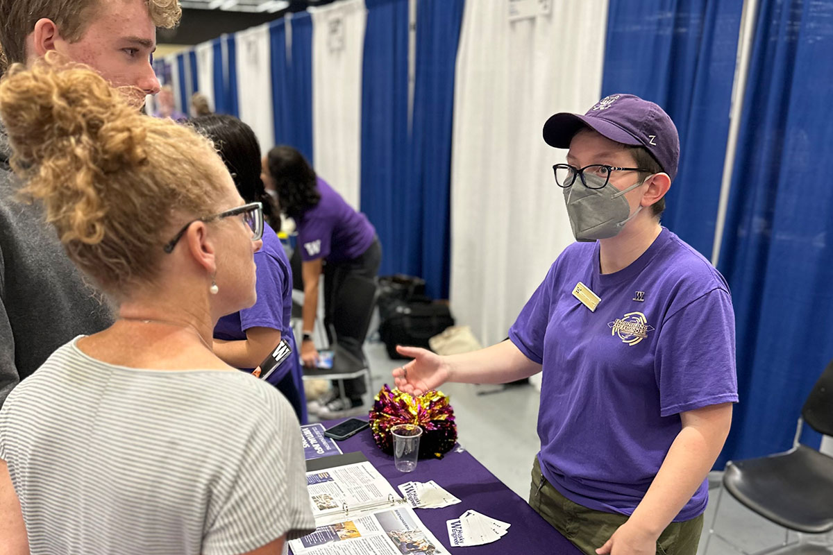 Student speaking to two people at a fair