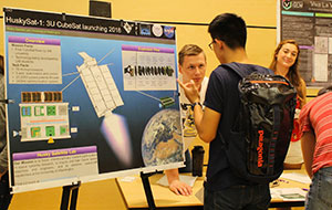 students at poster talking to welcome event attendees