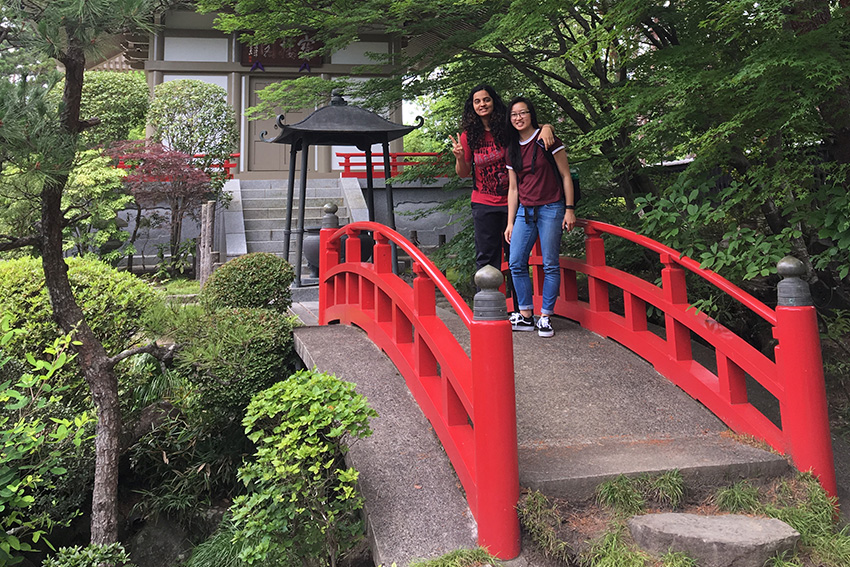 Two students standing on a red bridge