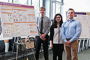 three members of the student team at a poster presentation