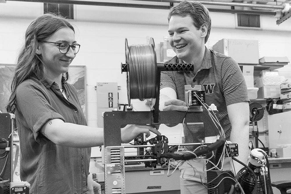 Two students working with a 3D printer