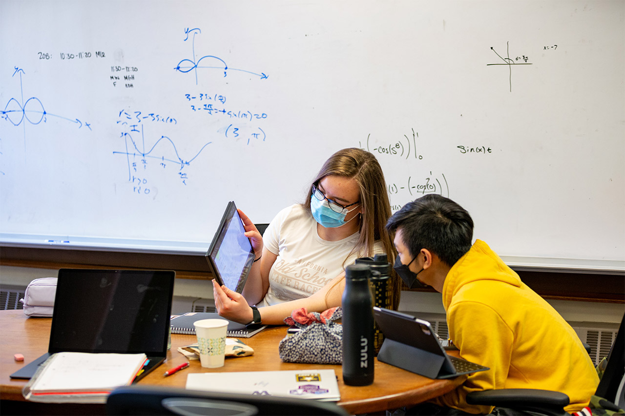 Students looking at tablet together in classroom setting