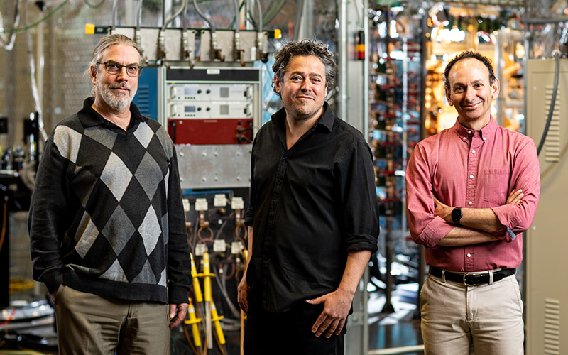 Three people standing in workshop space surrounded by machinery