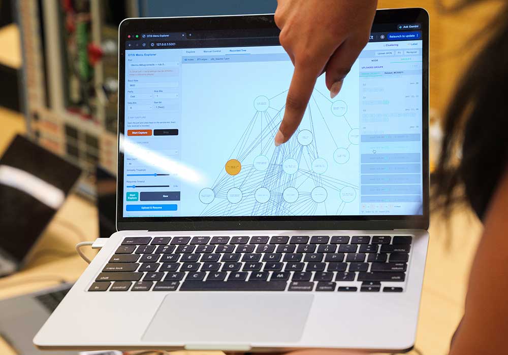 Student points at laptop displaying complex diagram