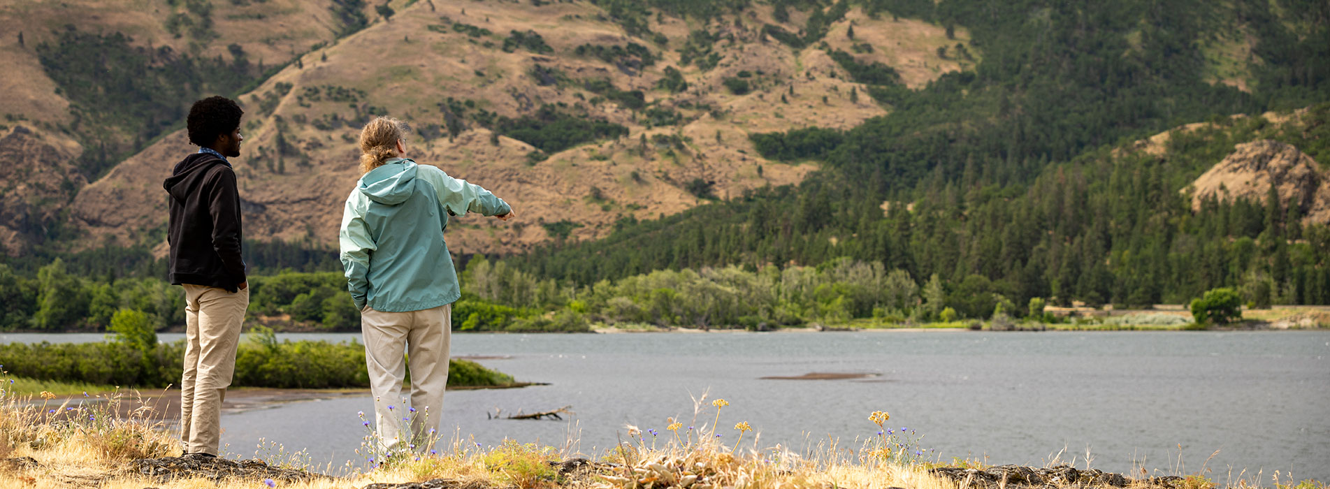 Two people overlooking a river and surrounding hills