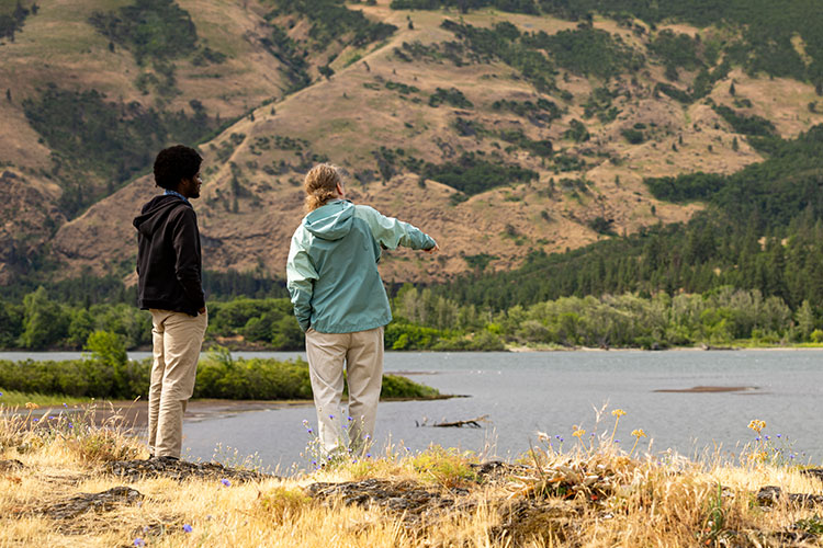 Two people overlooking a river and surrounding hills