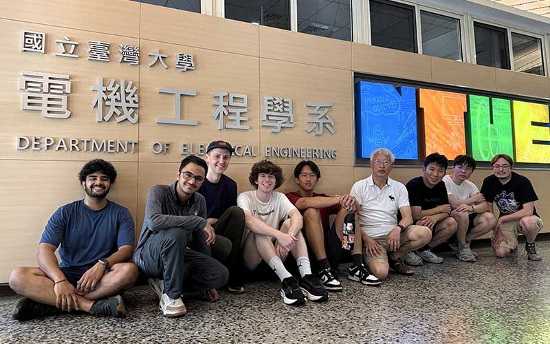 Group of students and faculty posing for picture in front of National Taiwan University Department of Electrical Engineering sign