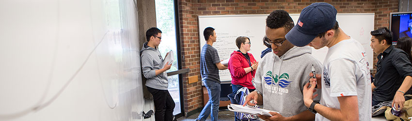 Two students looking down at a notebook inside a classroom