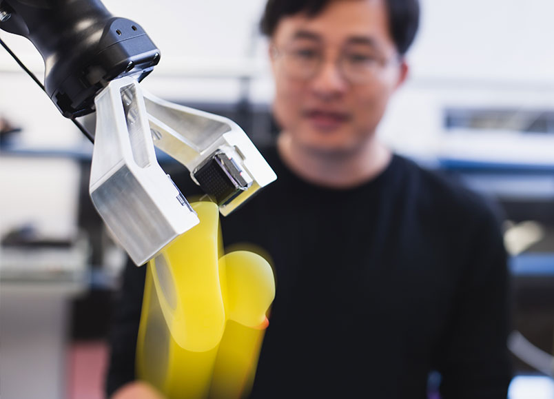 Xu Chen watching as robotic arm lets go of rubber duck