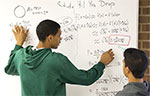 Devin Pegues, left, and Casiano Atienza work on a math problem at a whiteboard at UW