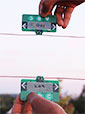 two card-sized devices with antennas held near each other with pink-streaked sky in background