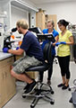 three young scientists, one looking through a microscope, examine a molecule they designed