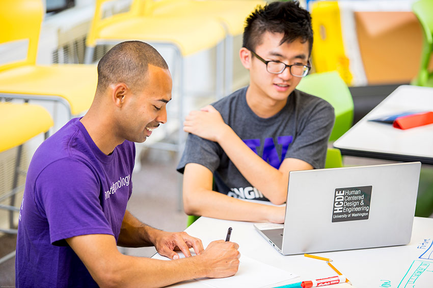 Two students sitting in front of a laptop computer