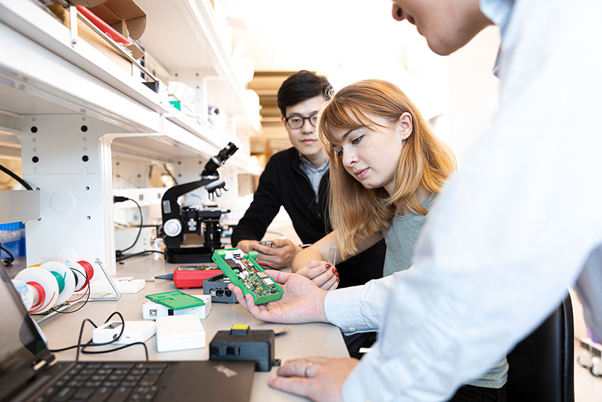 Three students inspecting the inner workings of a device