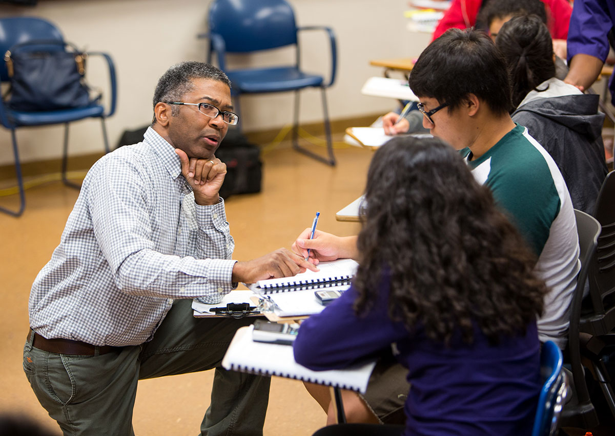 Sheldon speaking with two students in a classroom