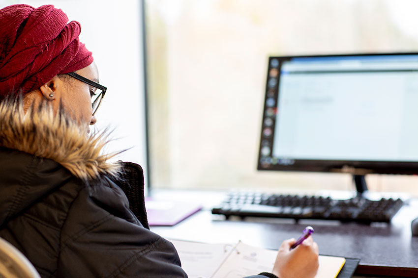 a female student writing in front of a computer