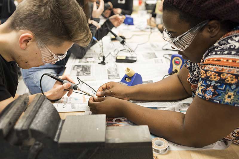 picture of students soldering at a table