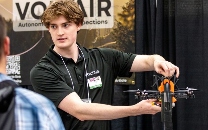 Student holds up drone in fair-setting