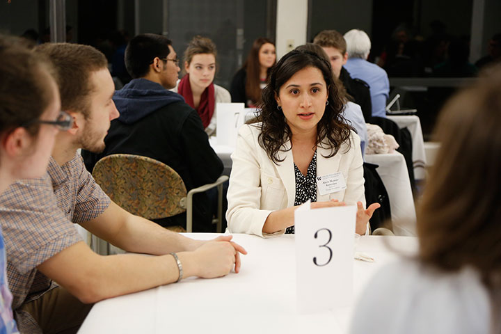 students and an alumna conversing in a crowded room