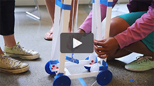 video still of student adjusting a machine with wheels and pulley