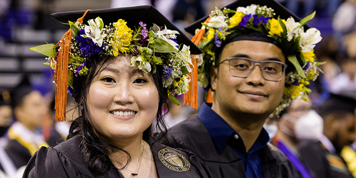 Two students at commencement wearing cap and gowns