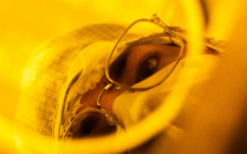 Researcher peering into a camera lens