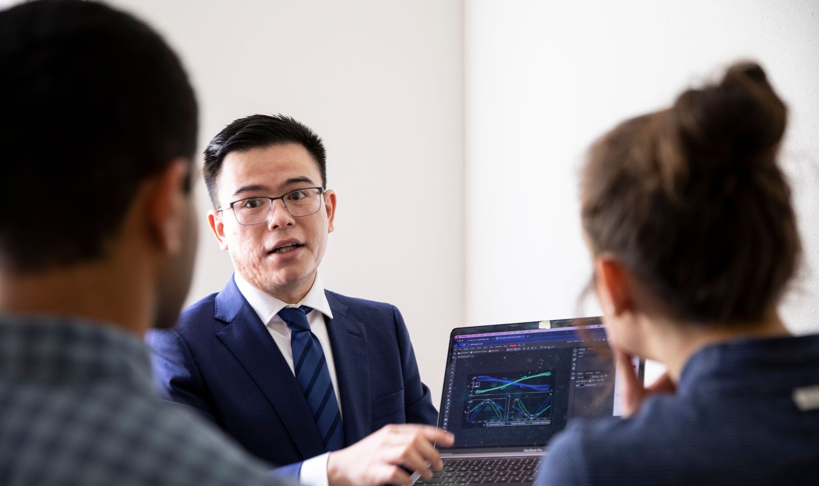 Professor showing two students a laptop screen, which shows a data visualization