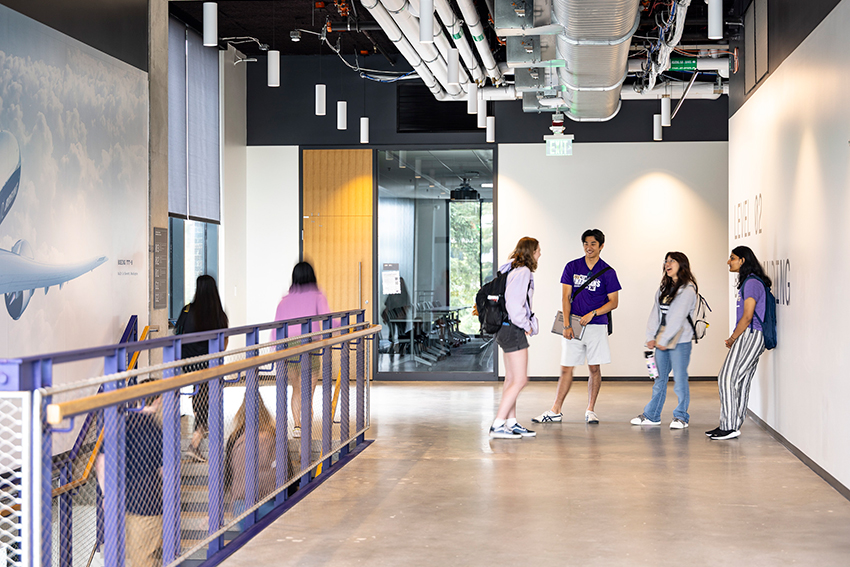 Students standing in an IEB hallway near a staircase.