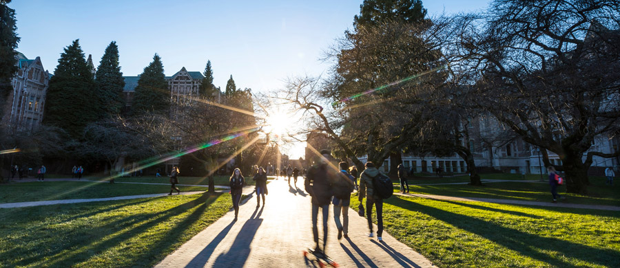 People walking across campus as sun rises in the horizon