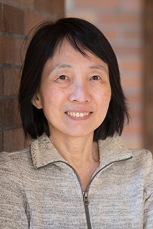 A head-and-shoulders photo of UW ECE Professor Lih Lin, standing in a brick hallway outside of the UW ECE building on the UW Seattle campus