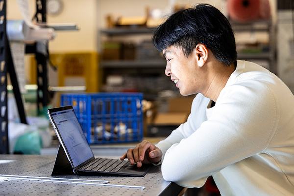 Student working on laptop in an engineering workshop
