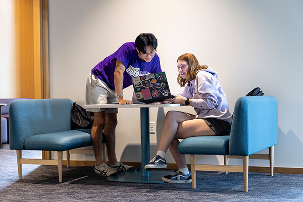 Two students looking at a laptop working together