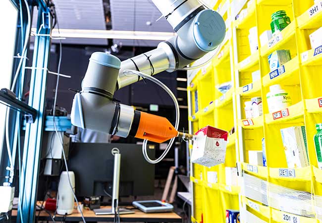 Robot arm practicing grasp by holding on to box from shelf of items