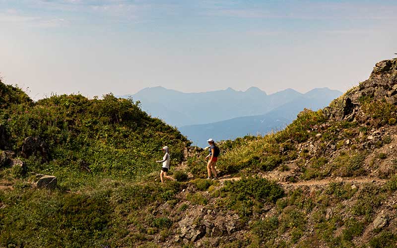 Two people hiking to project location; mountainous scenery in the background