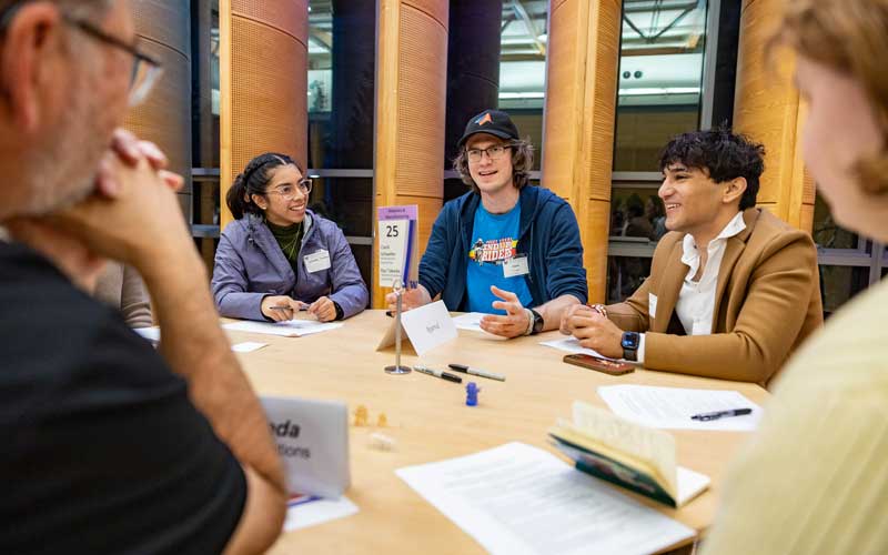 Students and mentors sitting around round table talking