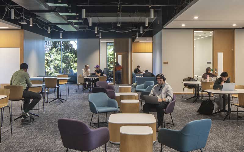 Students sitting working on laptops around a floor in the IEB