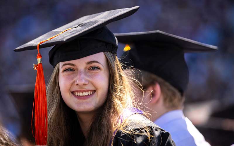 Smiling student wearing cap and gown at Commencement ceremony