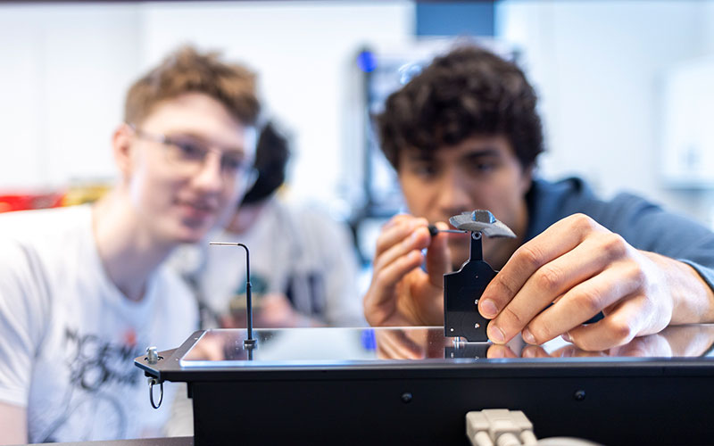 Two students working on model plane part in a workshop space