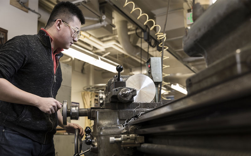 Student uses precision machining equipment in an engineering workshop, highlighting access to specialized tools funded to support student learning.