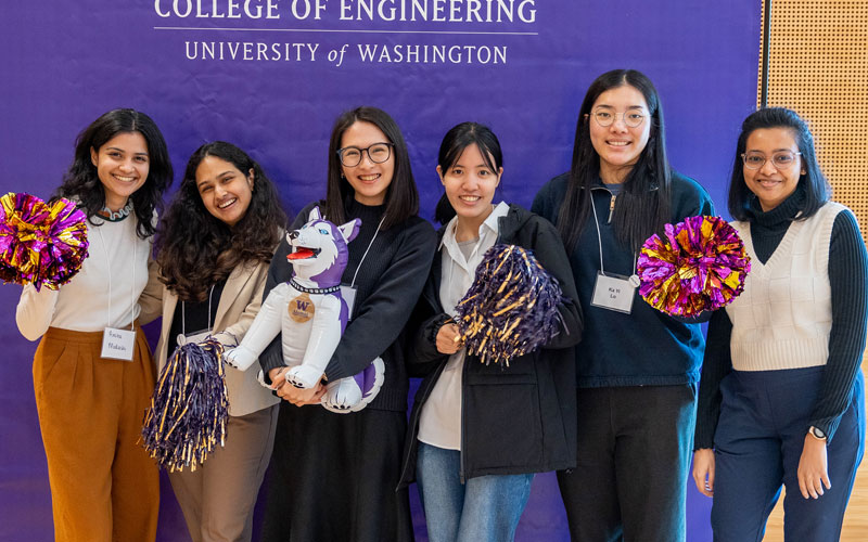 Group of WE Rise conference attendees pose for picture holding pom poms and other branded swag