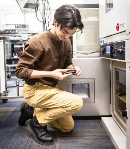 Student kneeling looking at a small battery