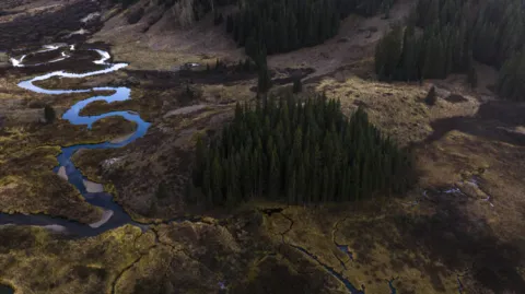 an aerial shot of a landscape with a river going through the lefthand side of the photo
