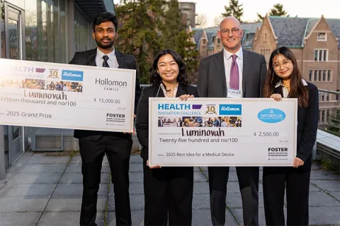 Four people smiling with large winning checks