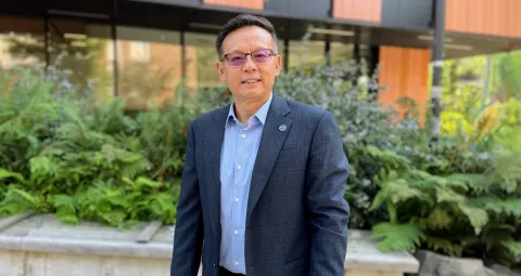 Juming Tang standing in front of a building on campus.